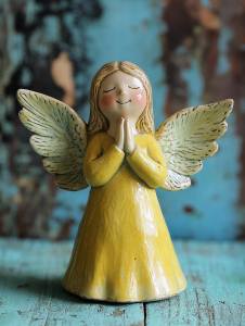 ceramic yellow angel on the green wooden table --style raw